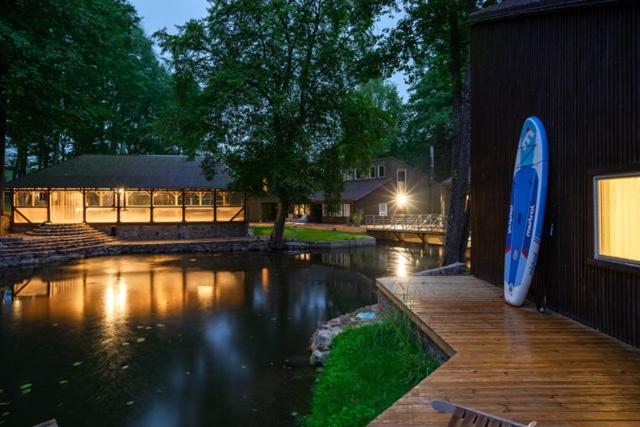 a surfboard sitting on a wooden deck next to a river at Vila Strėva in Kozelkiskes