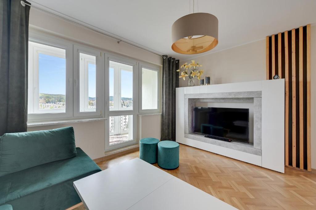 a living room with a fireplace and a green couch at Platinium Apartament Morski in Gdańsk