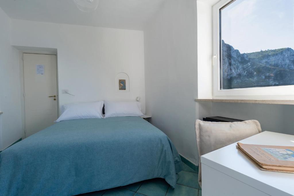 a bedroom with a bed and a table and a window at Albergo La Prora in Capri