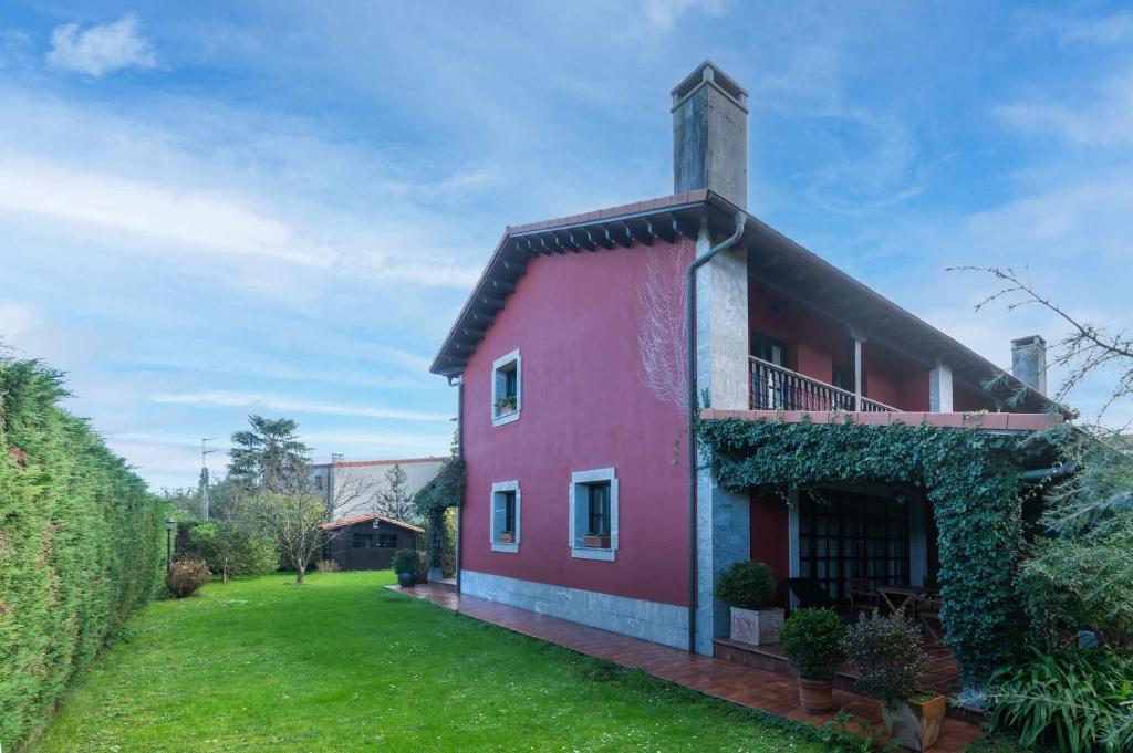 una casa roja con un patio verde y un edificio en Villa vacacional el Castañin, en Pancar