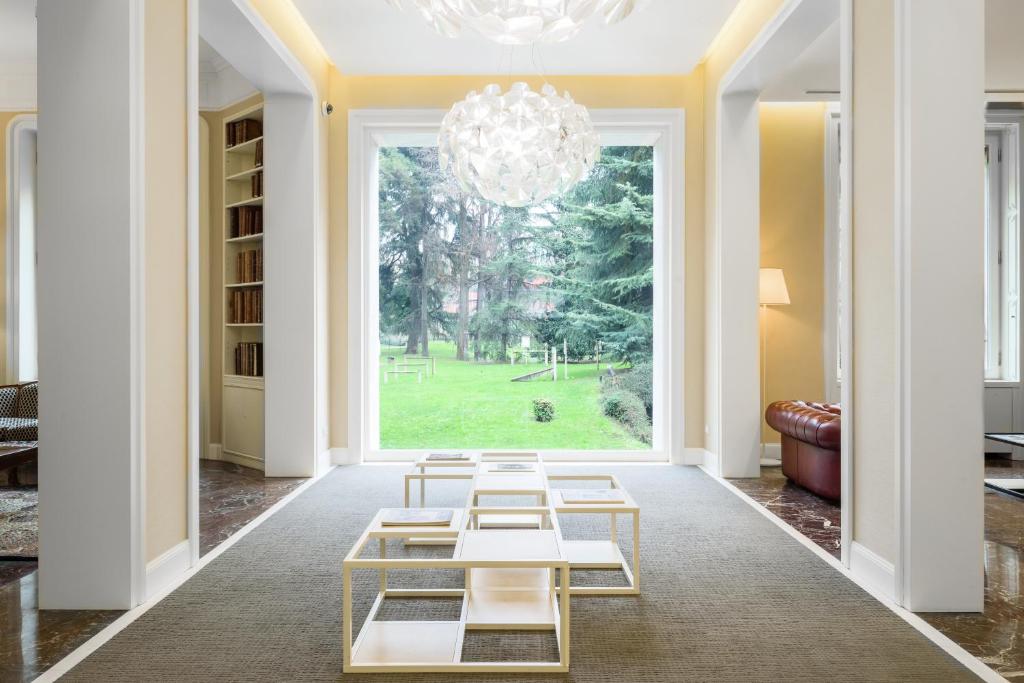 a living room with a chandelier and tables at Hotel Tiziano - Gruppo Mini Hotel in Milan