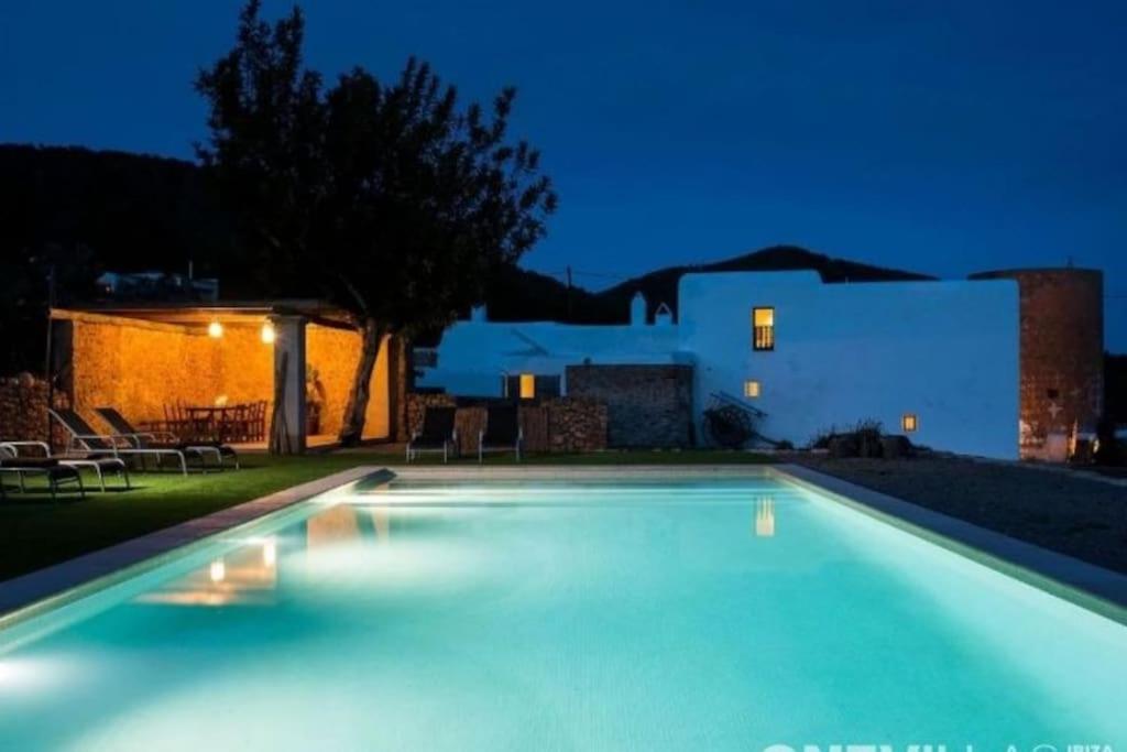 a swimming pool in front of a house at night at Cas Orvais con piscina y jardín in Sant Jordi