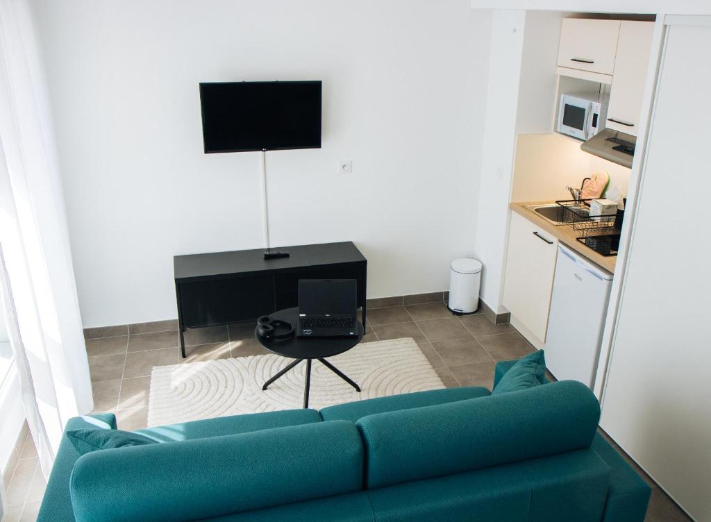 ein Wohnzimmer mit einem blauen Sofa und einem TV in der Unterkunft Twenty Business Flats Nice Angely in Nizza