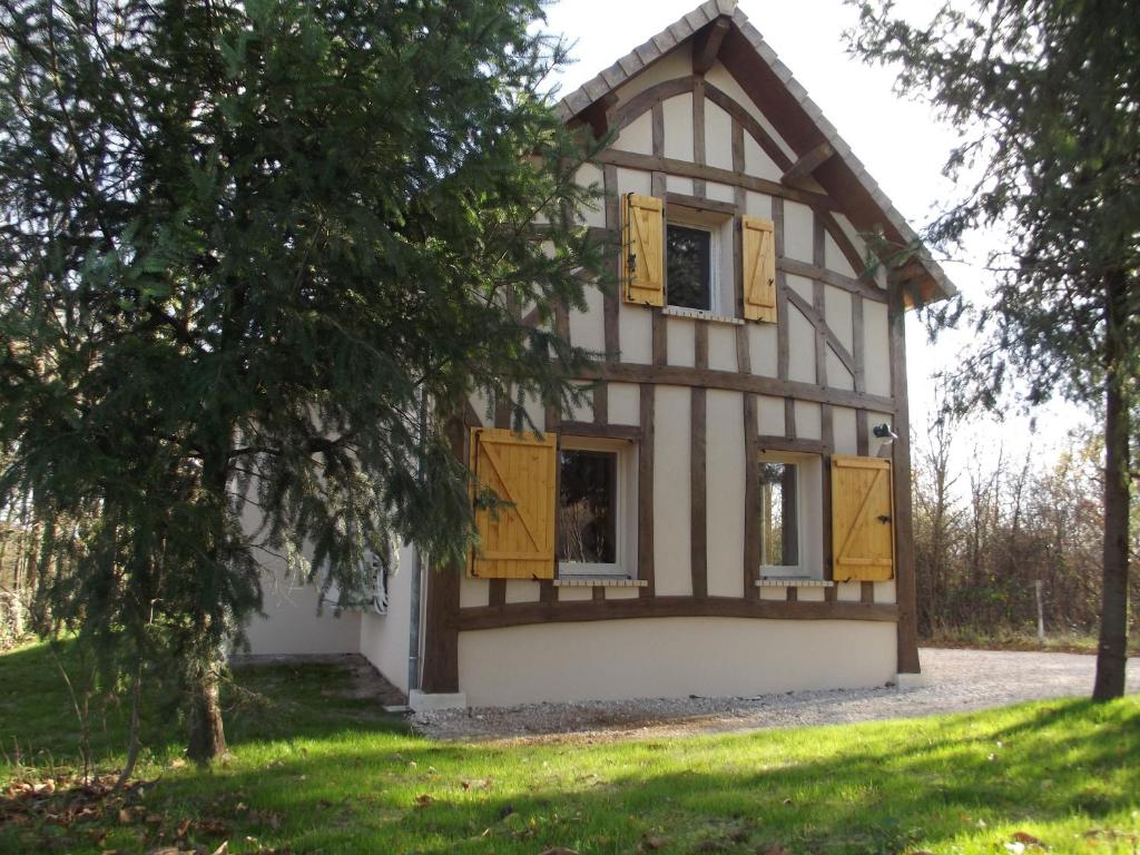 a house with yellow shutters and a tree at La Haute Bédinière in Crouy-sur-Cosson