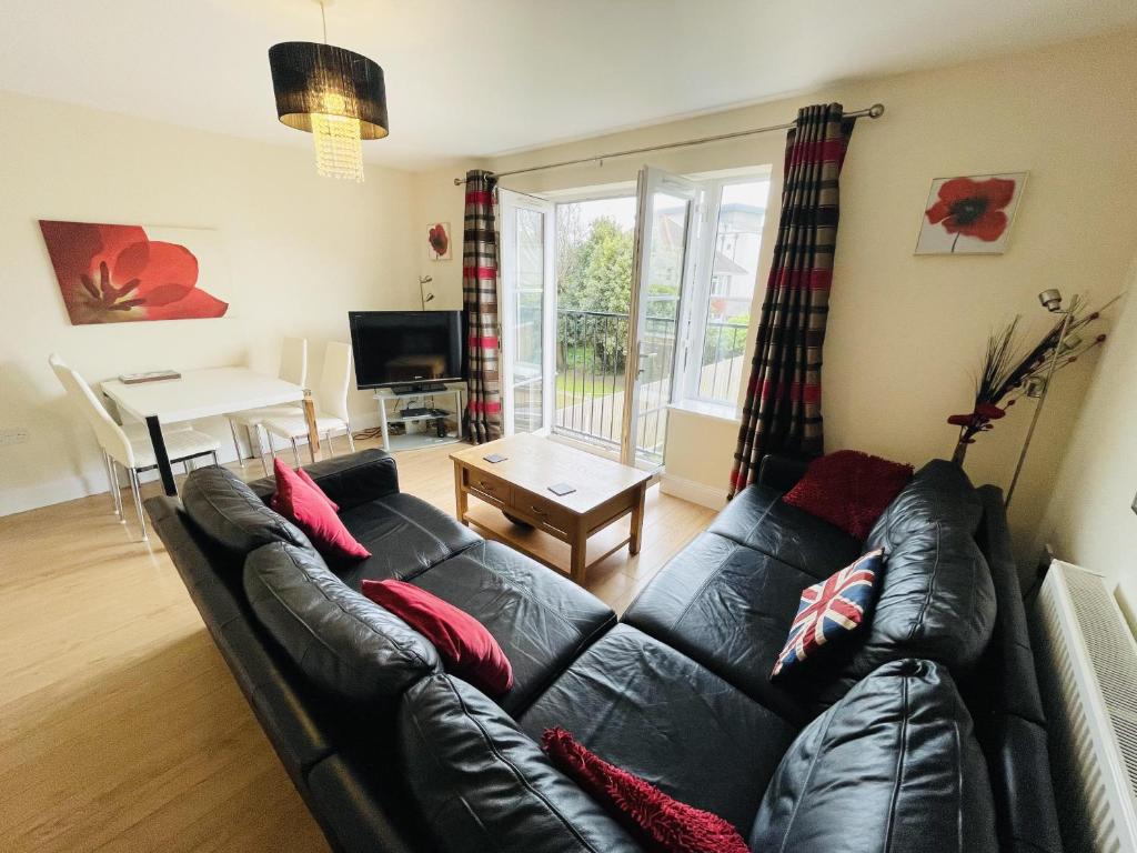 a living room with a black leather couch and a table at Flat 3 - Seabreeze - 2 bedrooms in Southbourne