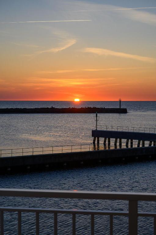 a pier with the sunset in the background at Sunset Boulevard 1 apt 9 Bulwar Zachodzącego Słońca 1 w Marina Royale in Darlowko