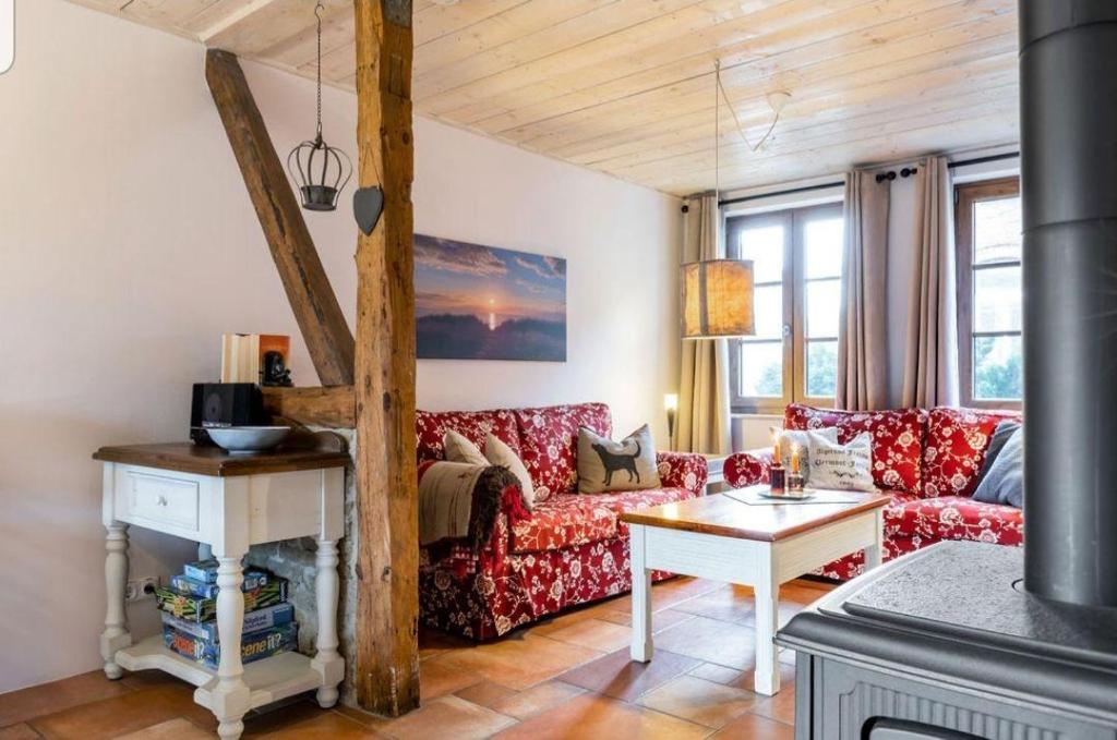 een woonkamer met een rode bank en een tafel bij Kamin-Haus-Nr-2-mit-Sauna-in-Burg in Fehmarn