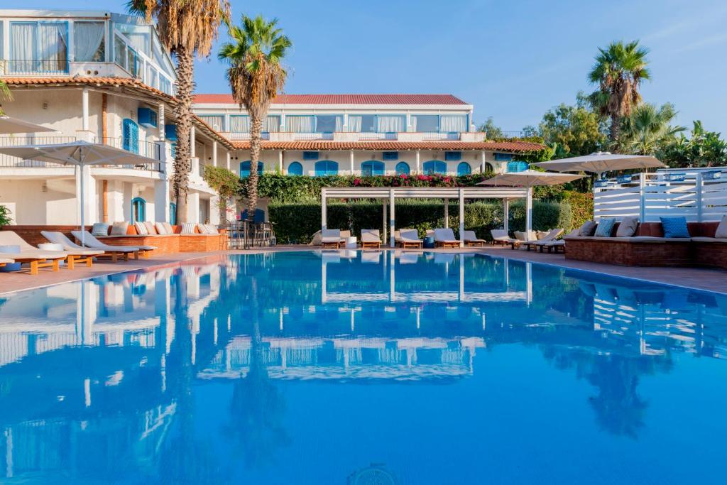 een zwembad voor een gebouw met palmbomen bij Le Dune Sicily Hotel in Catania