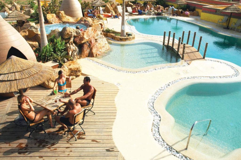 um grupo de pessoas sentadas numa mesa perto de uma piscina em Desert Springs Resort em Vera