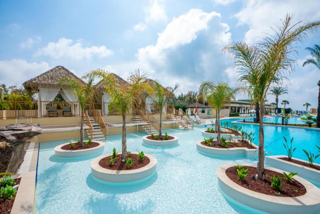 a resort pool with palm trees in the middle at Liberty Hotels Lara in Lara