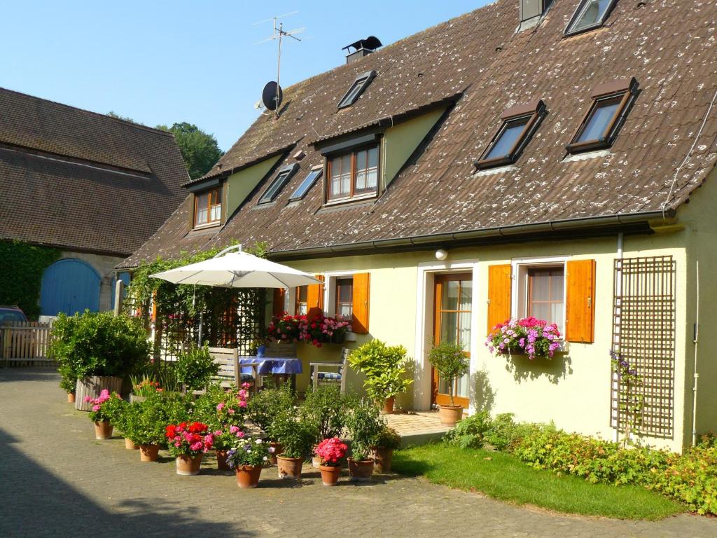 a house with flowers and an umbrella in front of it at Gästehaus am Brombachsee in Pfofeld