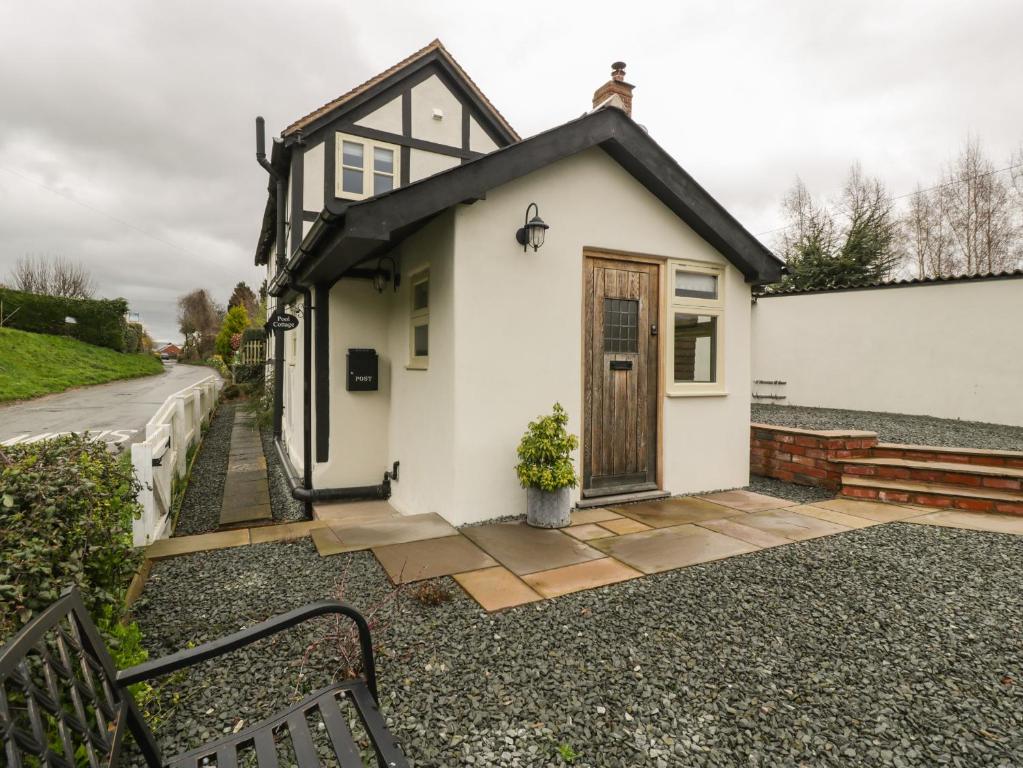 ein kleines weißes Haus mit einer Holztür in der Unterkunft Pool Cottage in Hereford