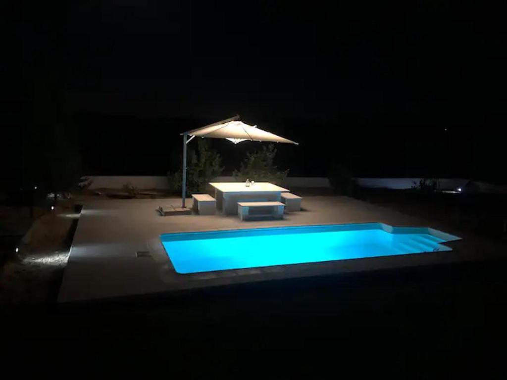 una piscina por la noche con sombrilla en Cheerful 2-bedroom Villa with pool 