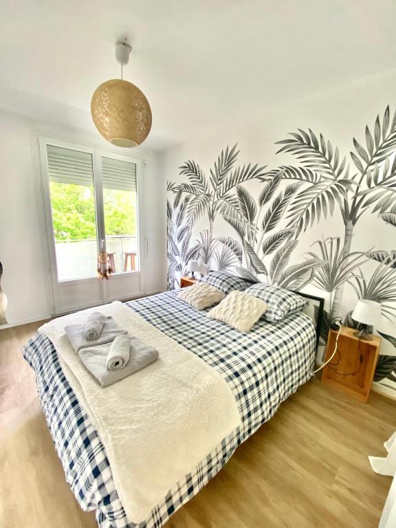 - une chambre avec un grand lit et du papier peint tropical dans l'établissement Superbe appartement au calme avec parking gratuit., à Mérignac