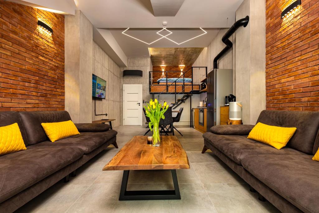 a living room with brown couches and a wooden table at Industrial-style 2BD Loft with Parking Spot in Plovdiv