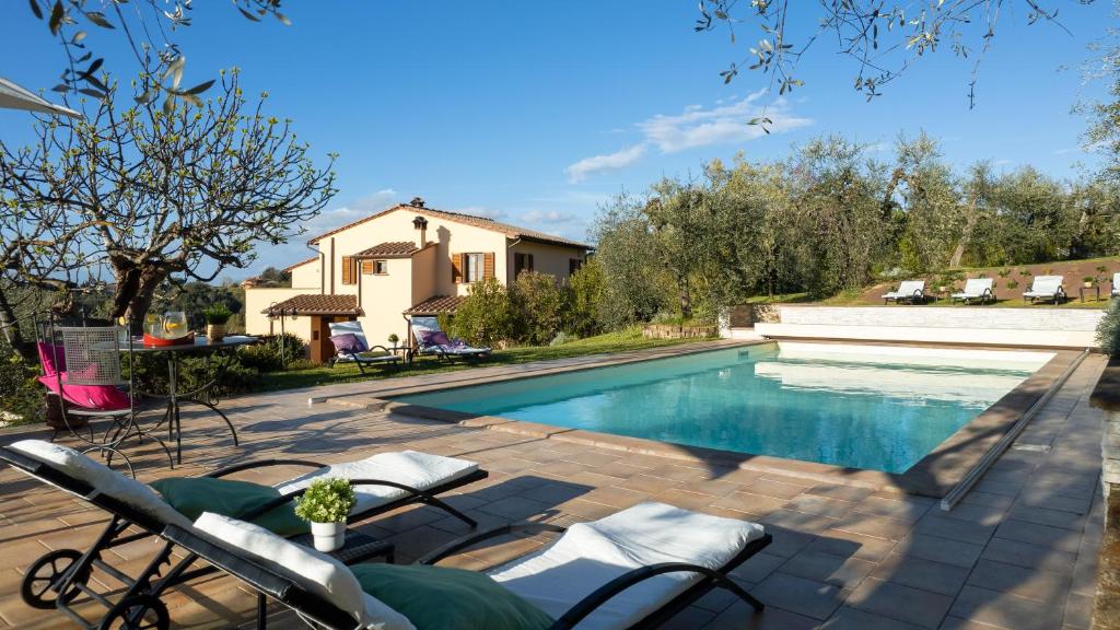 a swimming pool with chairs next to a house at La Villa nell'Isola Verde 12, Emma Villas in Casciana Terme