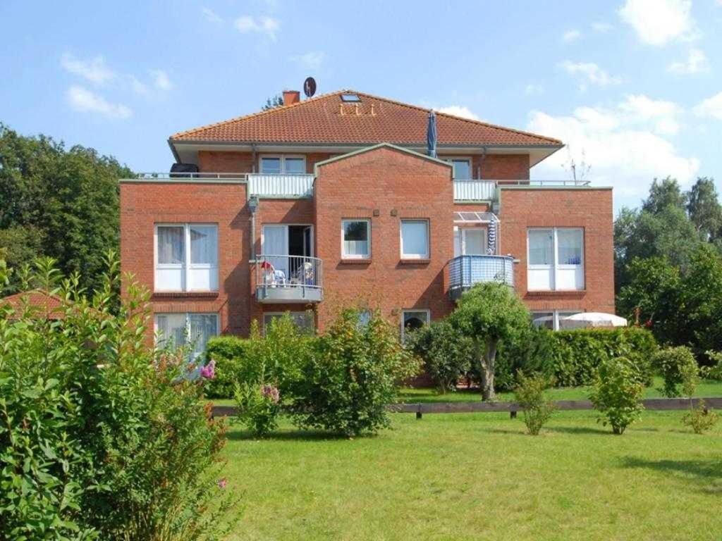 une grande maison en briques rouges avec une cour d'herbe dans l'établissement Goosbrink Whg 18, à Boltenhagen