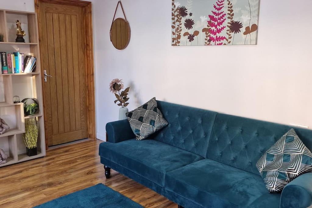 a living room with a blue couch and a door at 1 Bedroom Studio in Eltham