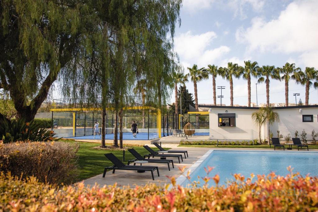 una piscina con bancos y palmeras en un parque en B&B Villa Seta, en Agrigento