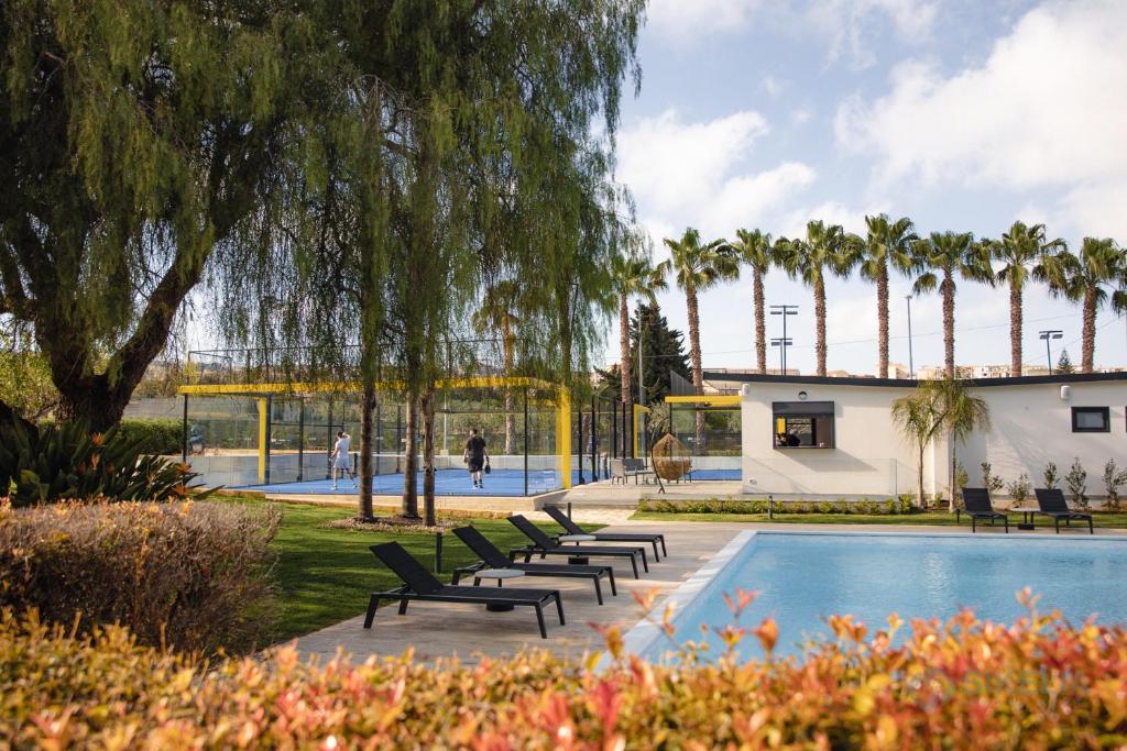 una piscina con panchine e palme in un parco di B&B Villa Seta a Agrigento