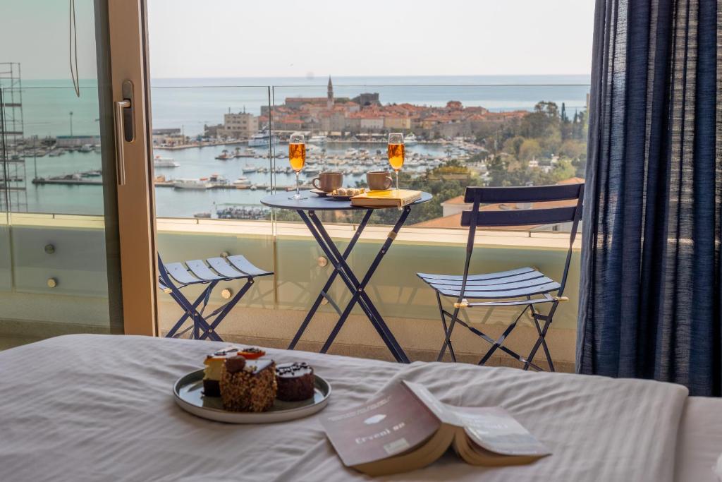 a room with a bed and a balcony with a table with desserts at City Apartments 2 in Budva