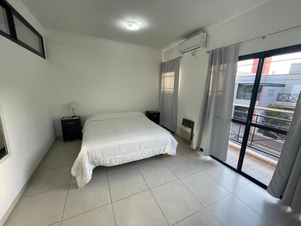 1 dormitorio con cama blanca y ventana grande en Departamentos Céntricos Modernos - Pagos en USD - Consultar Disponibilidad por Teléfono en Gualeguaychú