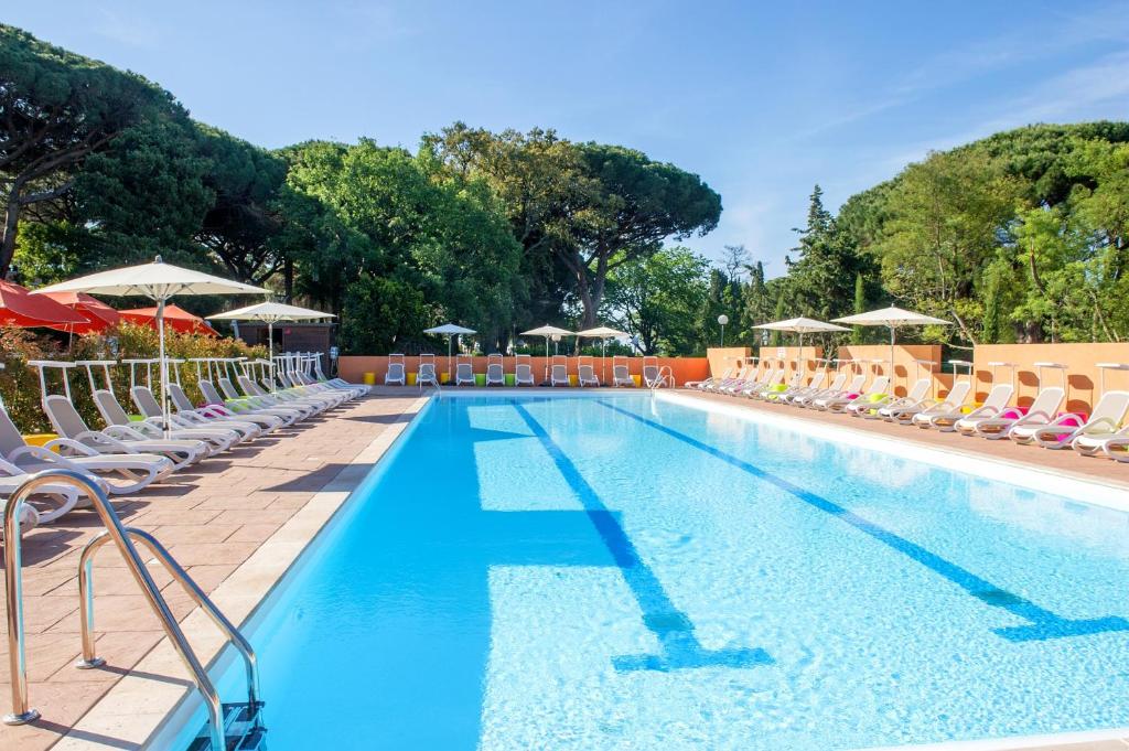 a large swimming pool with chairs and umbrellas at Village Club Miléade Les Issambres -Val d'Esquières in Les Issambres