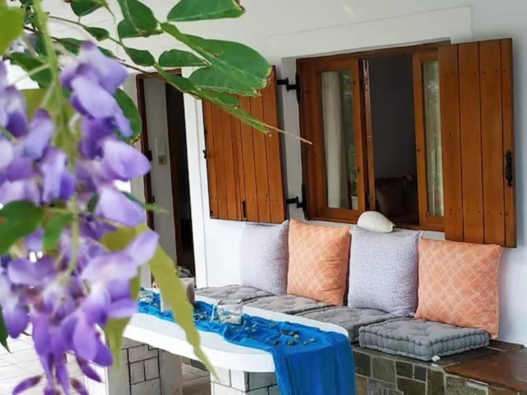 een woonkamer met een bank en paarse bloemen bij Traditional Olive House in Makry Gialos