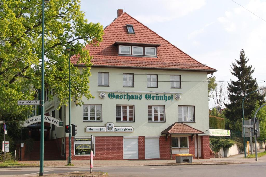 ein großes weißes Gebäude mit rotem Dach in der Unterkunft Gasthaus & Hotel Grünhof in Frankfurt (Oder)