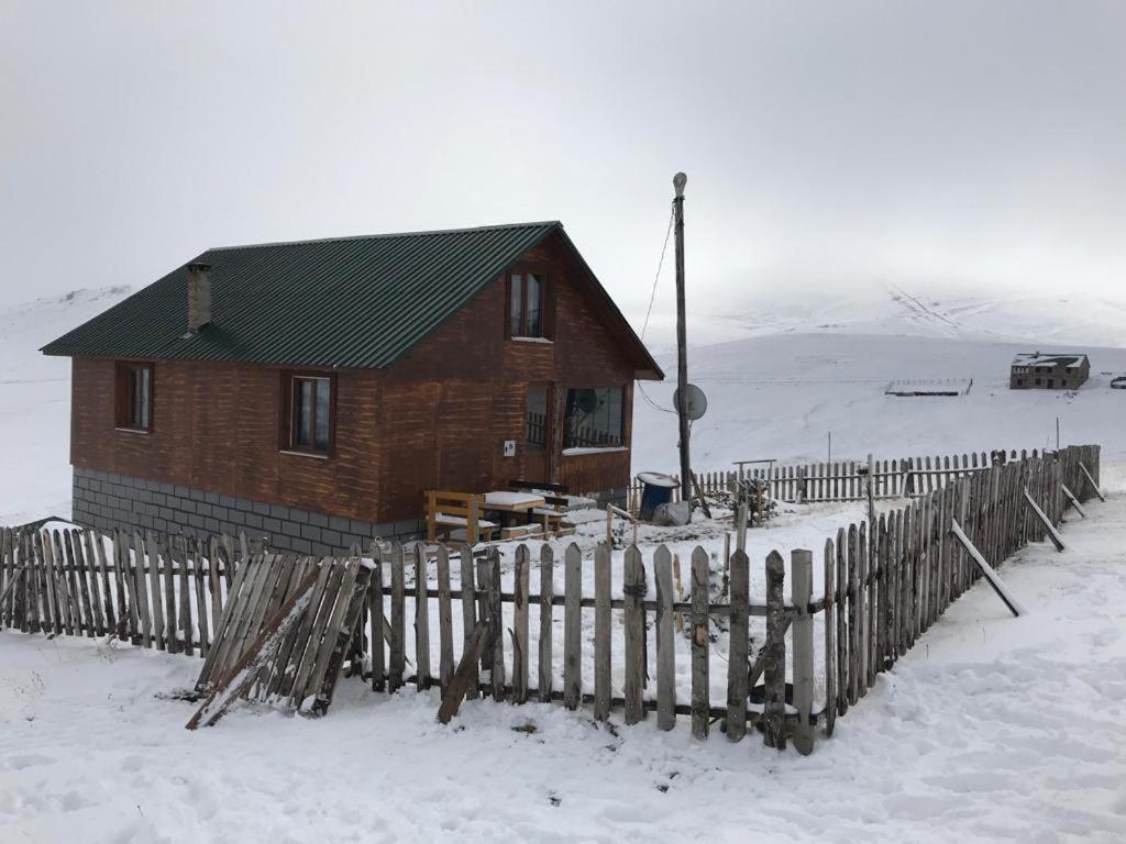 ein Holzhaus mit einem Zaun im Schnee in der Unterkunft KULAT DAĞ EVİ in Gumushane