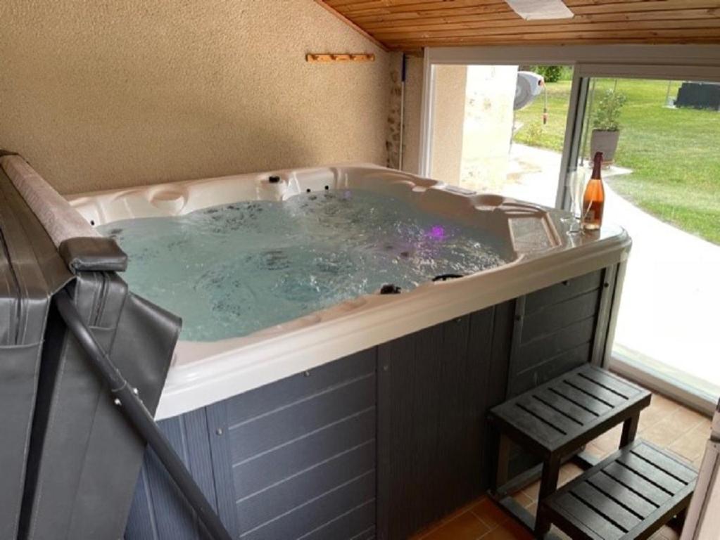 eine Whirlpool-Badewanne in einem Haus mit Bank in der Unterkunft GITE ROMANTIQUE in Cléré-les-Pins