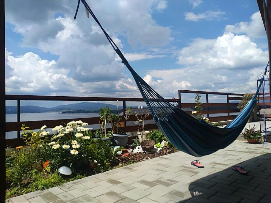a hammock on a balcony with a view of the ocean at Apartmán s terasou a výhledem na jezero Lipno in Kovářov