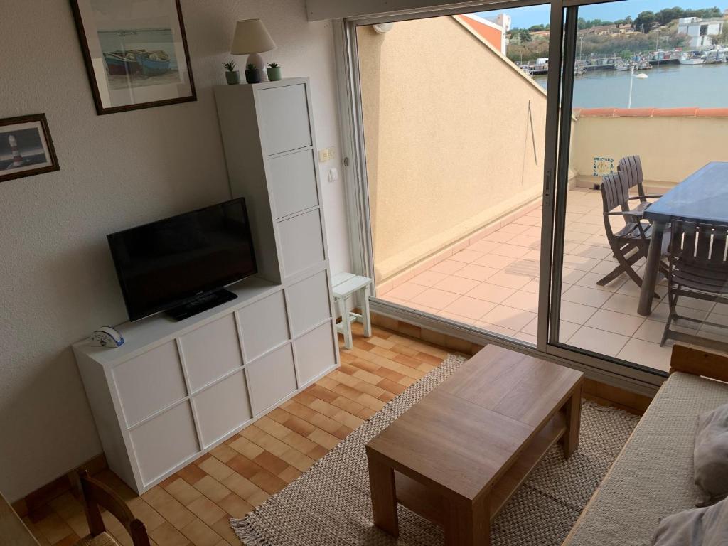 a living room with a flat screen tv on a white cabinet at Appartement calme vue sur l&#39;hérault et la mer in Agde