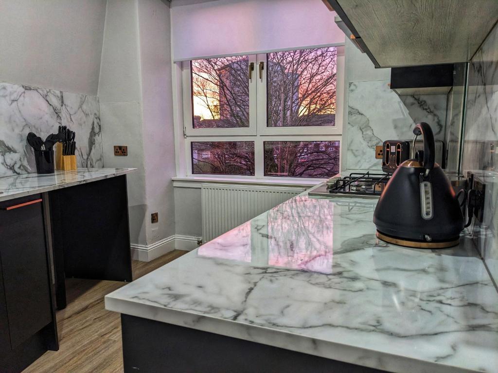 a kitchen with a marble counter top with a tea kettle at Sweeney Stays, Cadzow Apartment in Hamilton