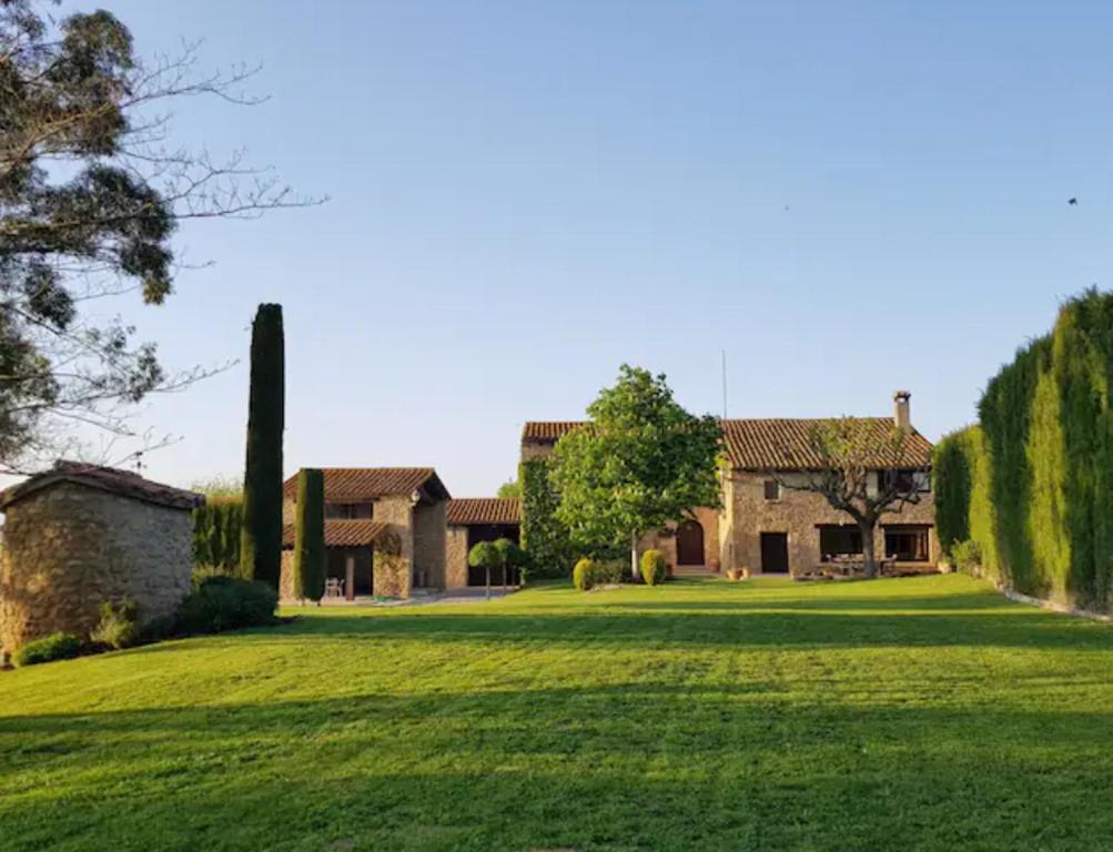 une maison avec une grande cour avec de l'herbe verte dans l'établissement Villa privada de lujo Can Riera, à Pujals dels Cavallers