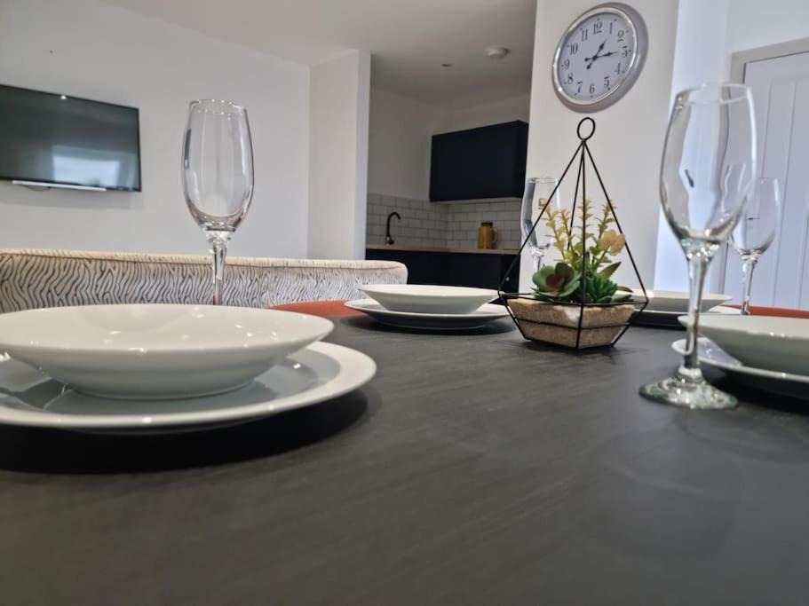 una mesa negra con platos y copas de vino. en Beautiful and Spacious 2-Bed Apartment: Home Away From Home en South Benfleet