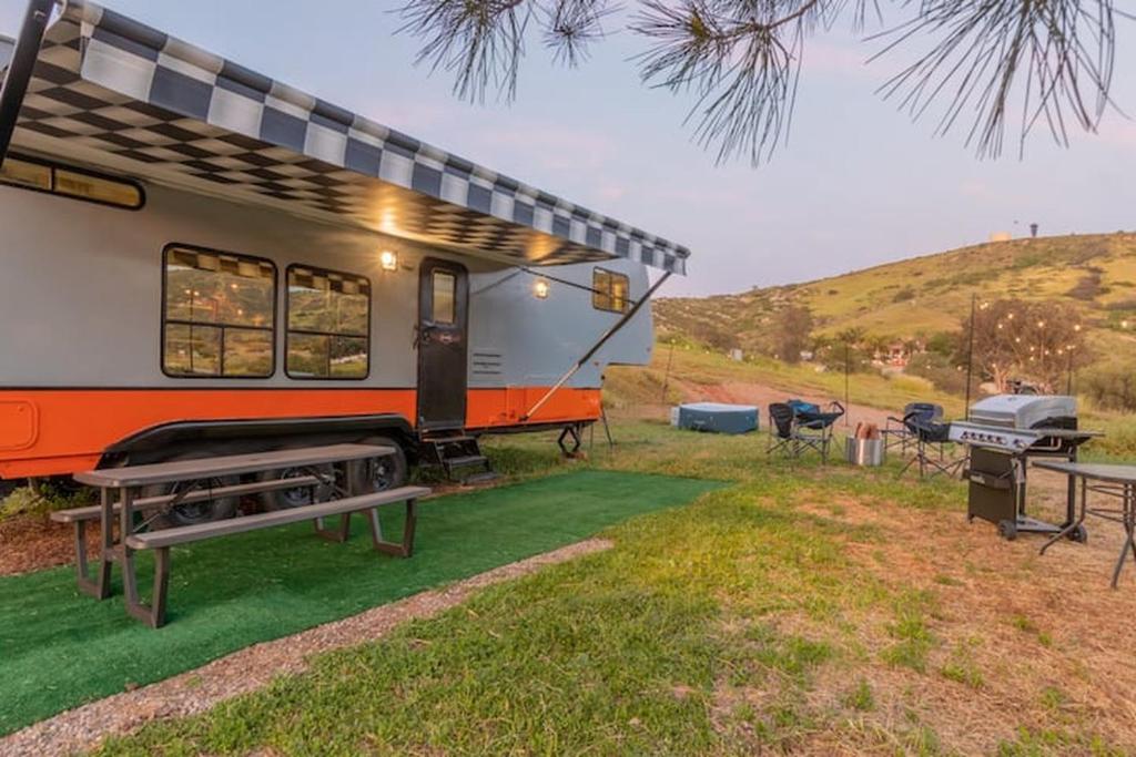 a caravan parked in a field with picnic tables and a grill at Harley Davidson Ranch Glampling With Kids Play Zone in Ramona