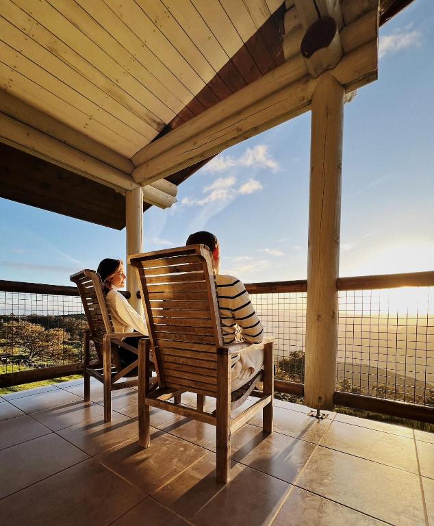 a man and a child sitting in chairs on a porch at Mountain Log Cabin O Garrano in Cabeceiras de Basto
