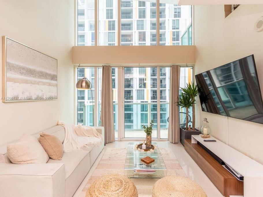 een woonkamer met een witte bank en een tv bij Beautiful Brickell Loft with Free Parking in Miami