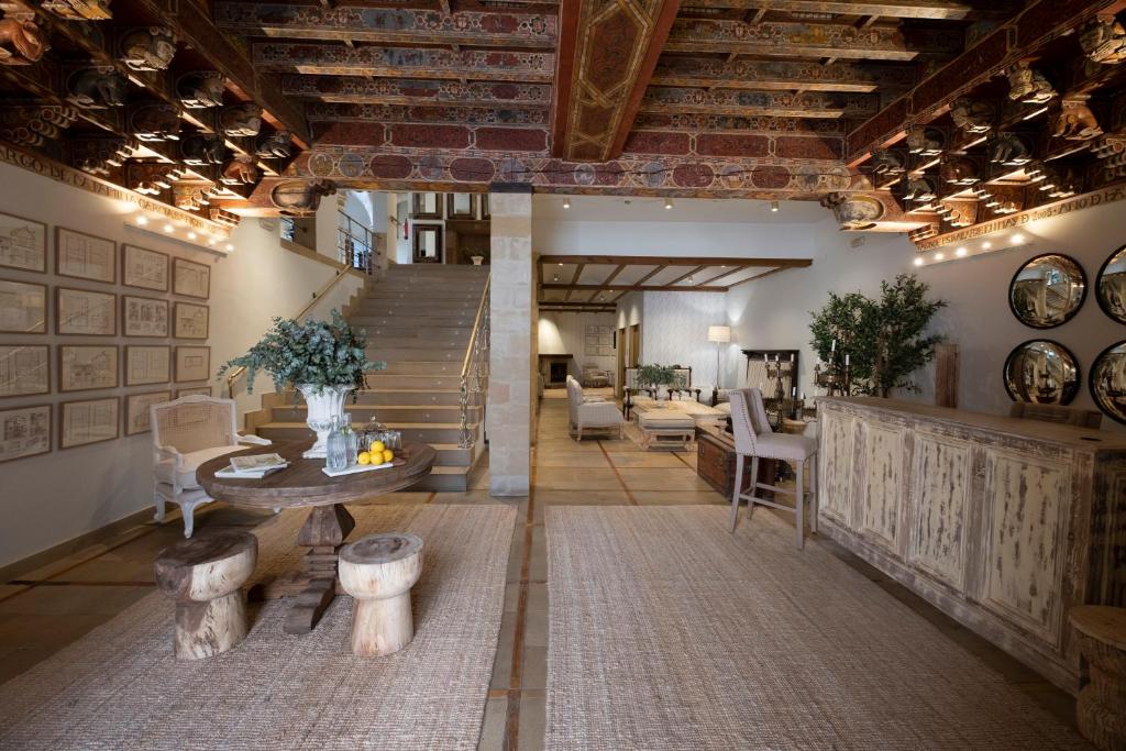 - un salon avec un escalier, une table et des chaises dans l'établissement Hotel Cetina Palacio de los Salcedo, à Baeza