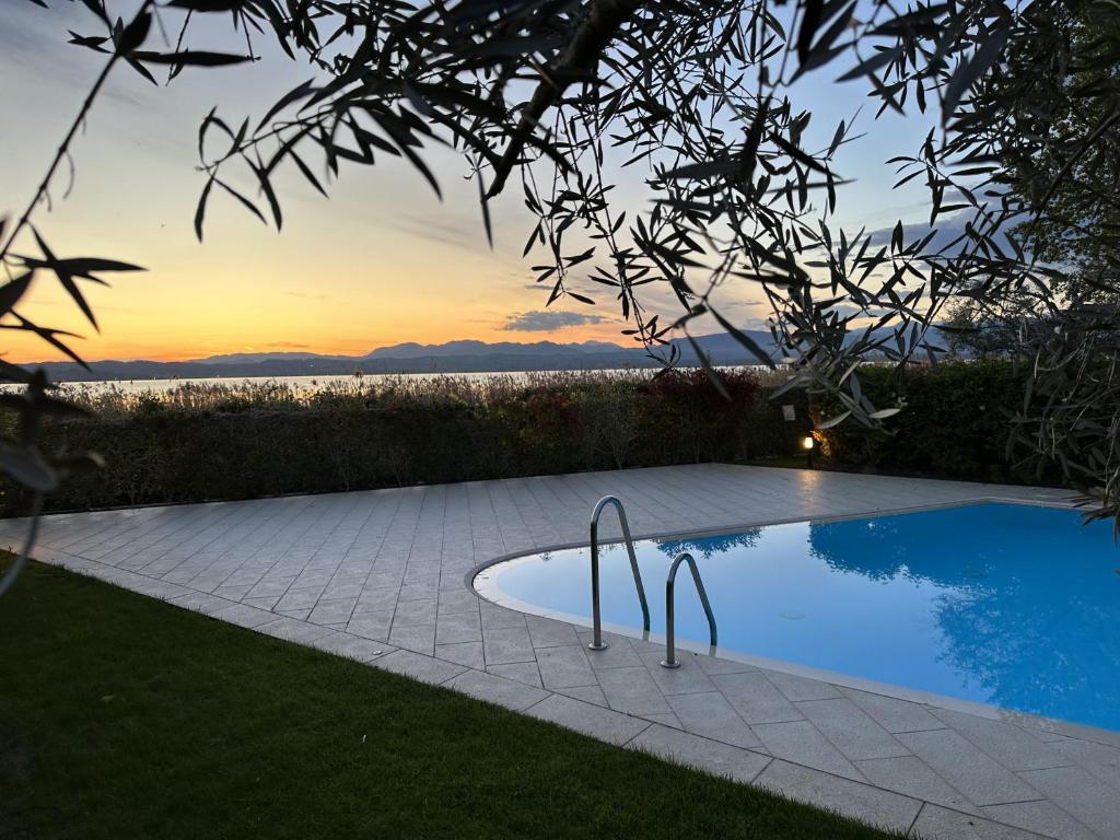 uma piscina num quintal com um pôr-do-sol ao fundo em Caesar Sirmione Luxury Apartment D8 em Sirmione