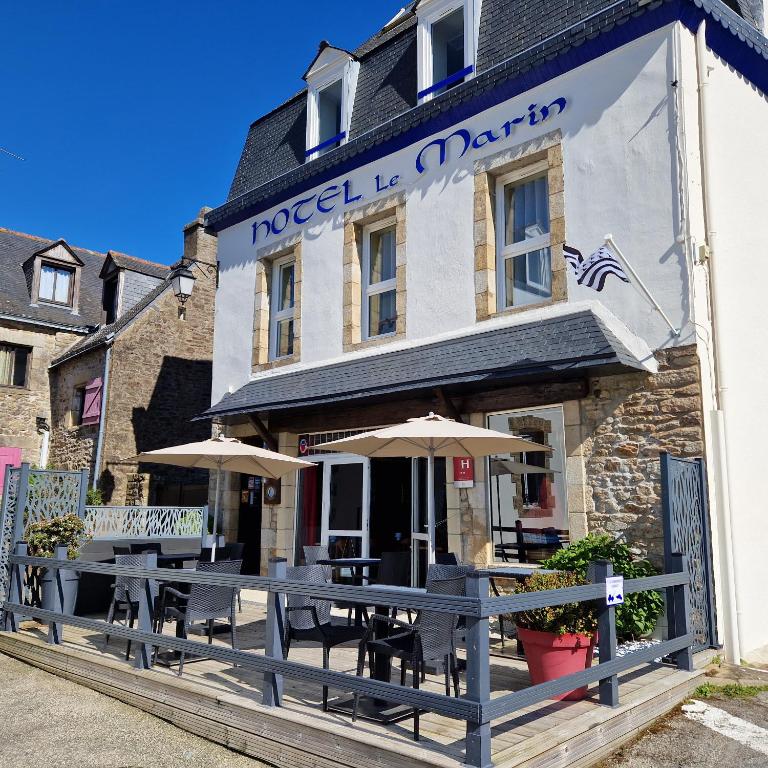 a restaurant with tables and umbrellas in front of a building at Hotel Le Marin in Auray