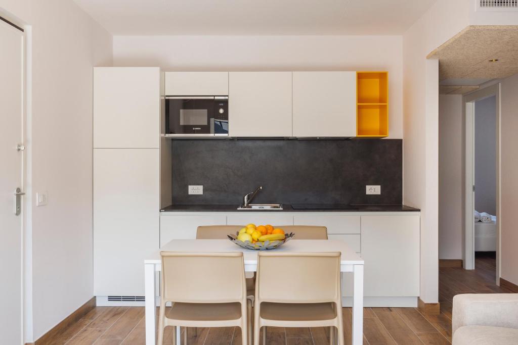 een keuken met witte kasten en een fruitschaal op een tafel bij Lake Side Suites in Riva del Garda