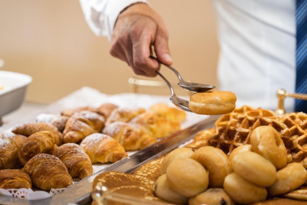 a person holding a spoon over a tray of pastries at Hotel dP Olbia - Sardinia in Olbia
