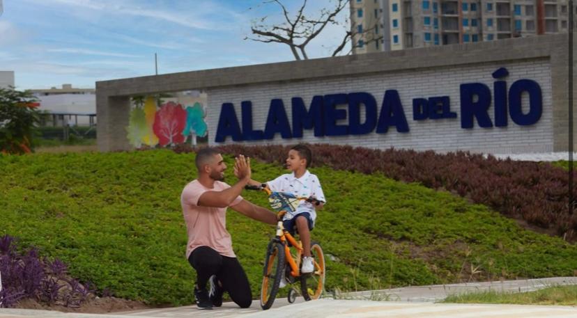 een man die een jongen een high five geeft op een fiets bij APARTAMENTO ALAMEDA DEL RIO in Barranquilla