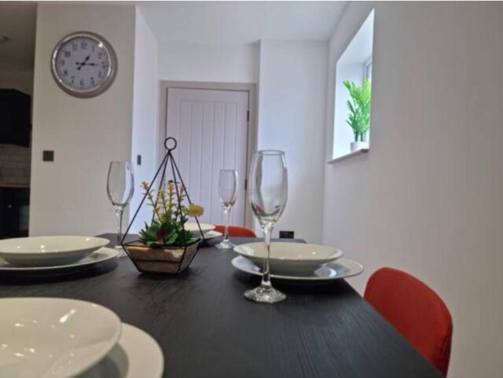a dining room table with wine glasses and a clock at IR Benfleet south in South Benfleet