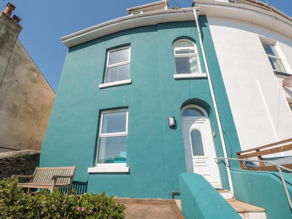 een blauw-wit huis met een bankje ervoor bij 2 North Furzeham Road in Brixham