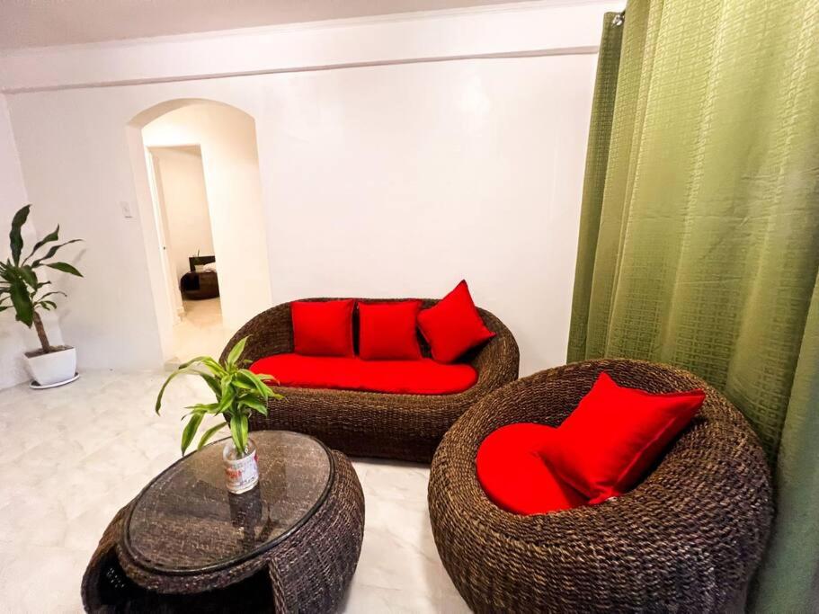 - un salon avec deux chaises en osier et des oreillers rouges dans l'établissement Affordable 3 Bedroom Lodge (Free Wi-Fi + Netflix), à Ángeles