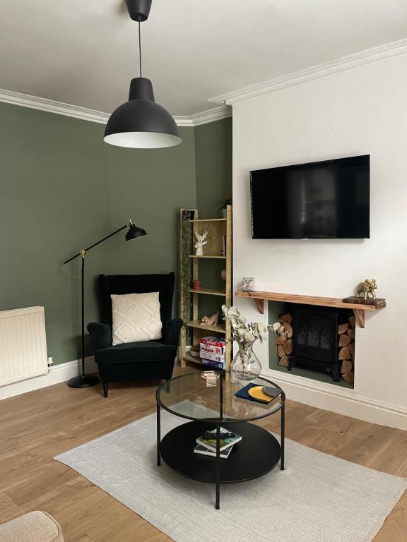a living room with a table and a tv on a wall at Hoole House- Bright and modern 2 bedroom house, close to Chester train station and the City Centre in Chester