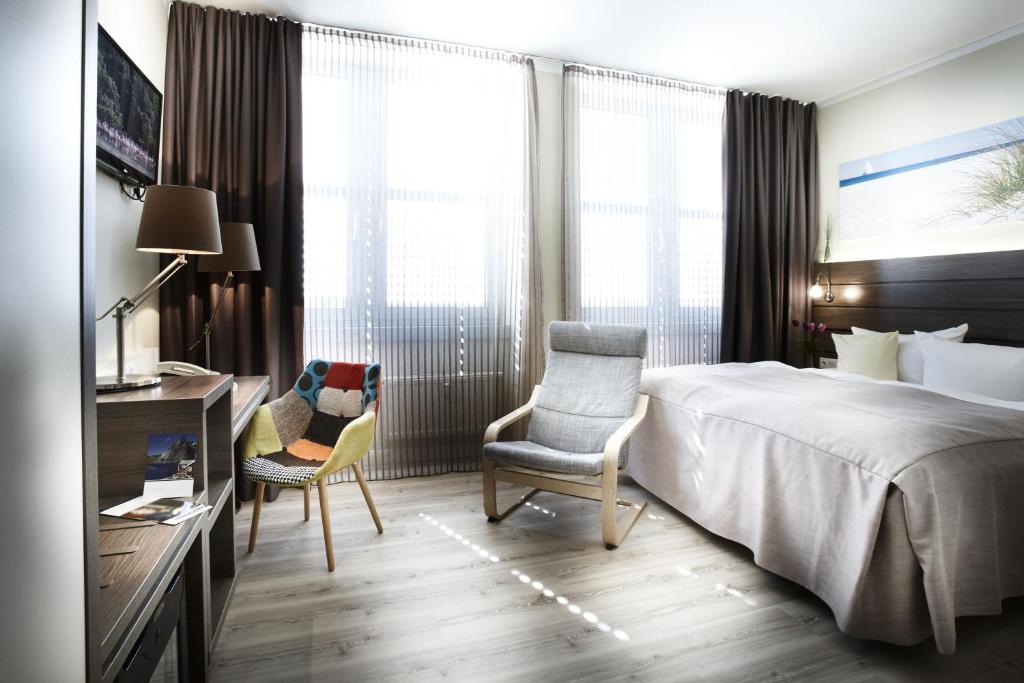 a hotel room with a bed and two chairs at Hotel Kiel by Golden Tulip in Kiel